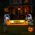 Illuminated skeleton Happy Halloween inflatable banner on a lawn at night