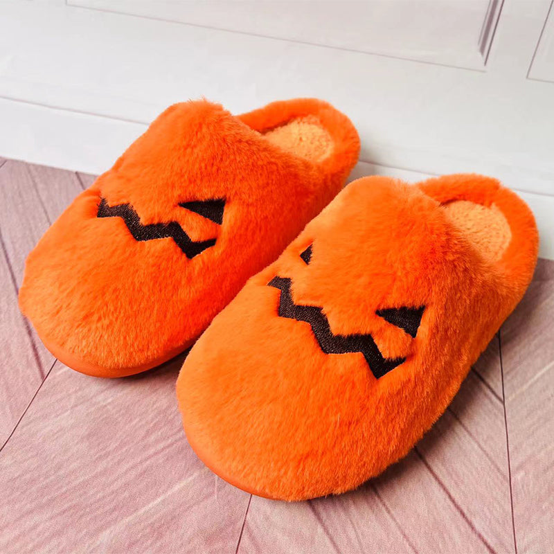 Pair of orange pumpkin face slippers on a wooden floor